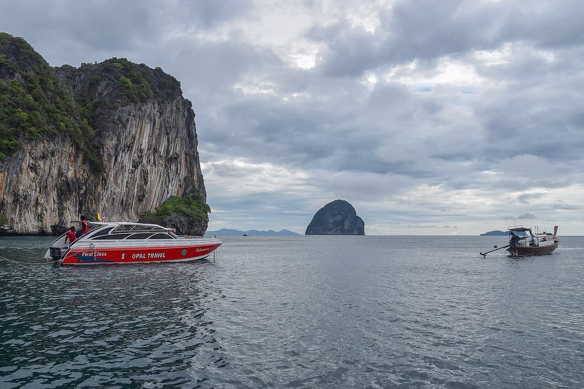 Speedboats and a longtail anchored beside the limestone cliffs of Koh Chueak