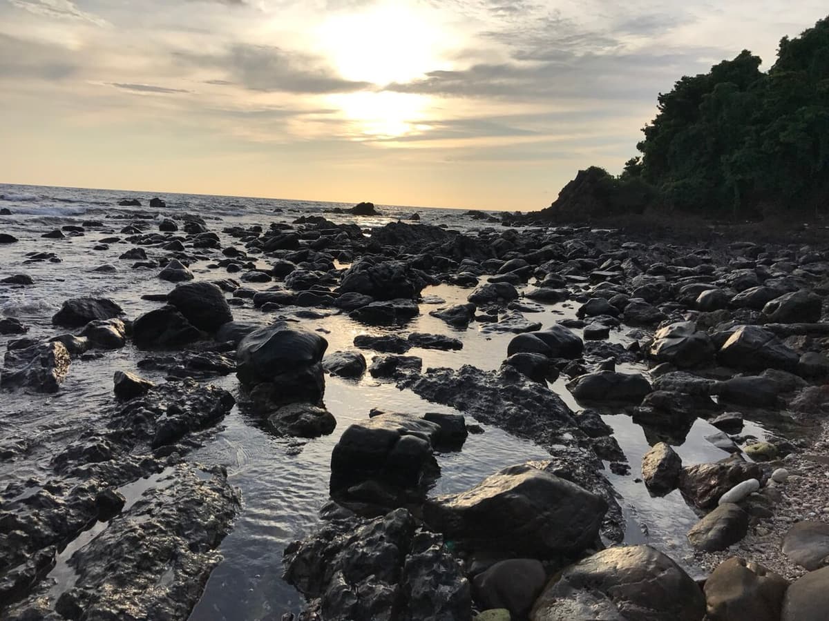 Rocks exposed at low tide and the evening sun over the sea at Koh Kradan