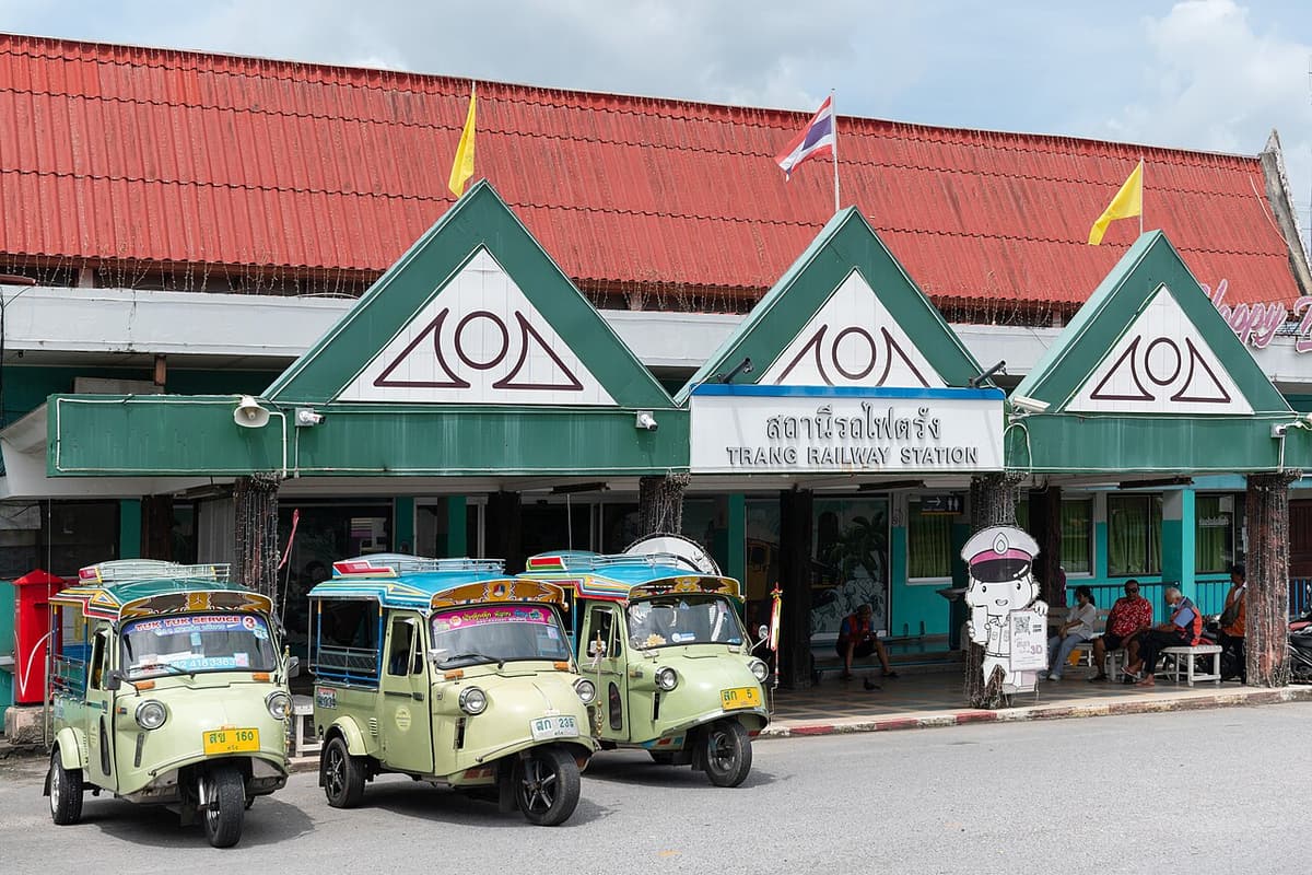 Green frog-faced tuk-tuks parked outside Trang railway station